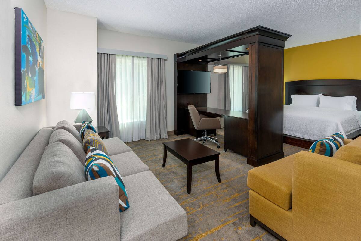 A hotel room with a sofa, armchair, and a bed.
