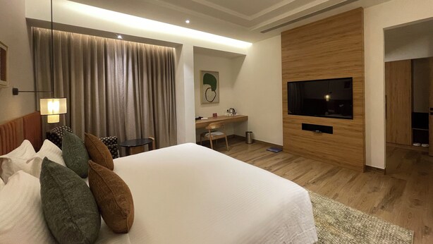A modern hotel room with a large bed, a desk, a television, and a ceiling fan. - Regency Tuticorin by GRT Hotels (Thoothukudi)