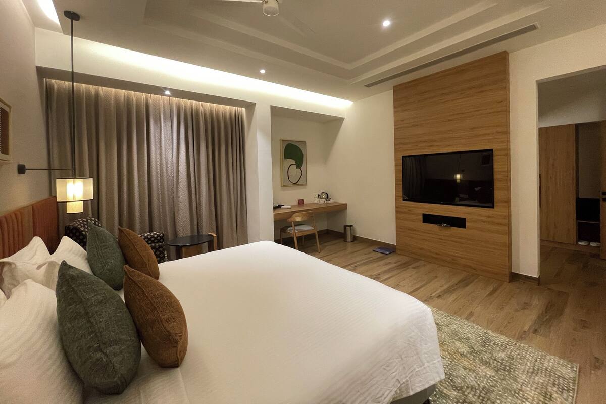 Ein modernes Hotelzimmer mit einem großen Bett, einem Schreibtisch, einem Fernseher und einem Deckenventilator.