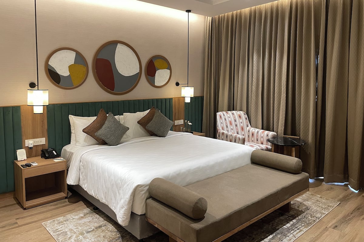 Ein modernes Hotelzimmer mit einem großen Bett, einem Sessel, einem Nachttisch und einer Lampe.