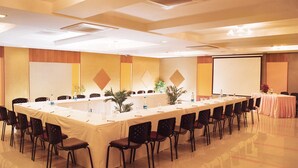 A conference room with a long table, chairs, and a projector screen. - Regency Tuticorin by GRT Hotels (Thoothukudi)