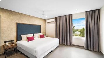 A hotel room with a large bed, a bedside table with a phone, and a view of the outdoors through the window.