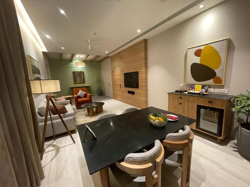 A modern dining area with a black table, wooden chairs, and a bowl of fruit.