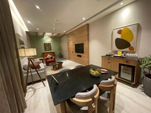 Un comedor moderno con una mesa negra, sillas de madera y un cuenco de fruta.