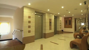A hotel lobby with a reception desk, seating area, and elevators. - Regency Tuticorin by GRT Hotels (Thoothukudi)