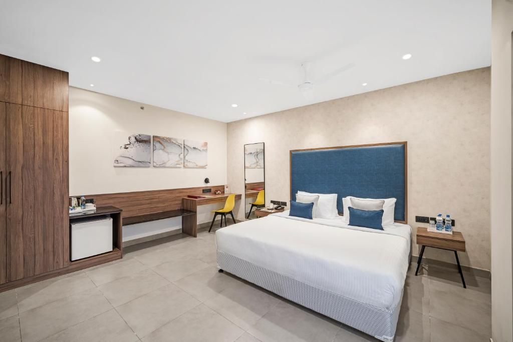 Ein modernes Hotelzimmer mit einem großen Bett, einem Schreibtisch, einem Stuhl und einem Kleiderschrank.