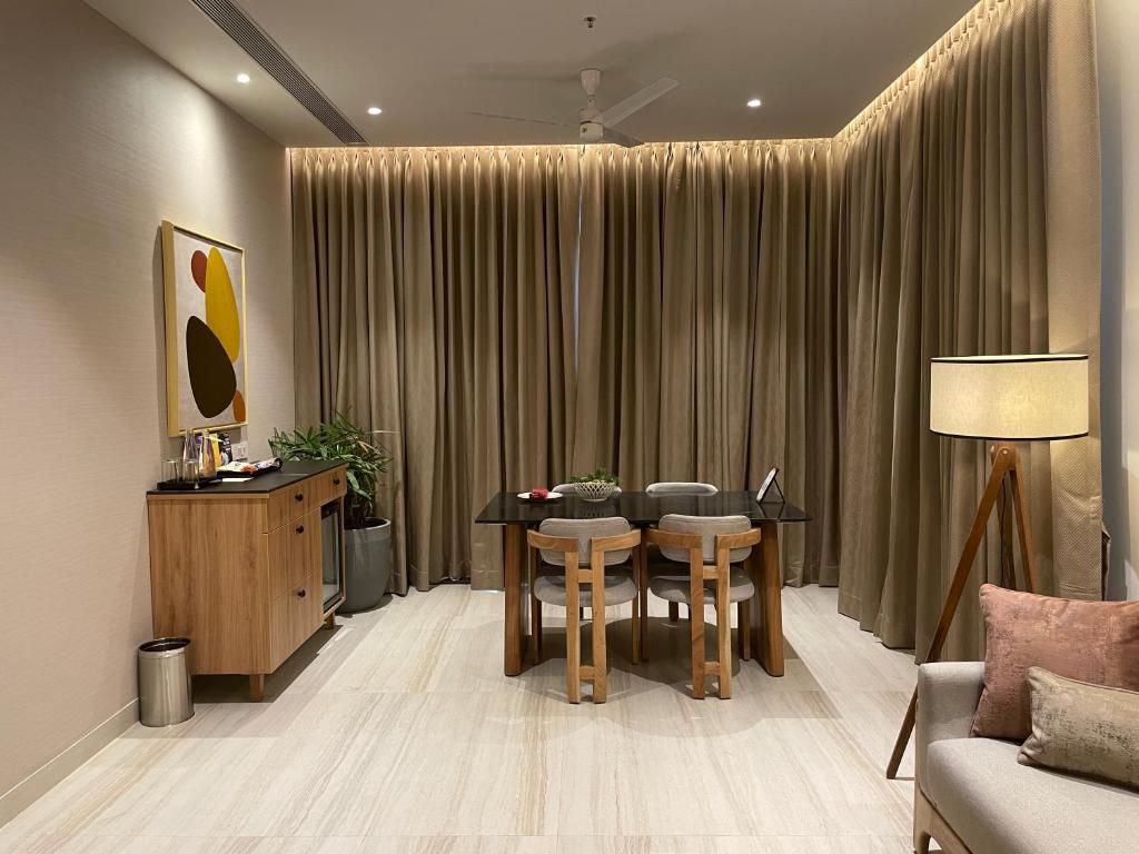 A modern living room with a dining table, chairs, a sofa, a lamp, and a cabinet.