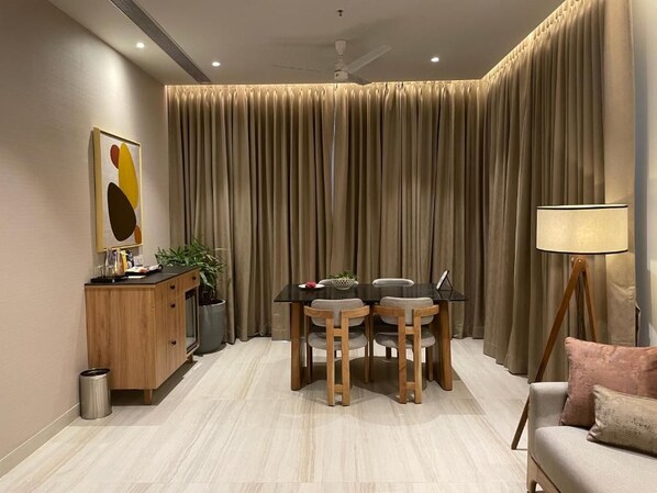 A modern living room with a dining table, chairs, a sofa, a lamp, and a cabinet.