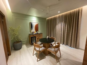 A dining area with a round table and chairs, a potted plant, a cabinet, and a painting on the wall.