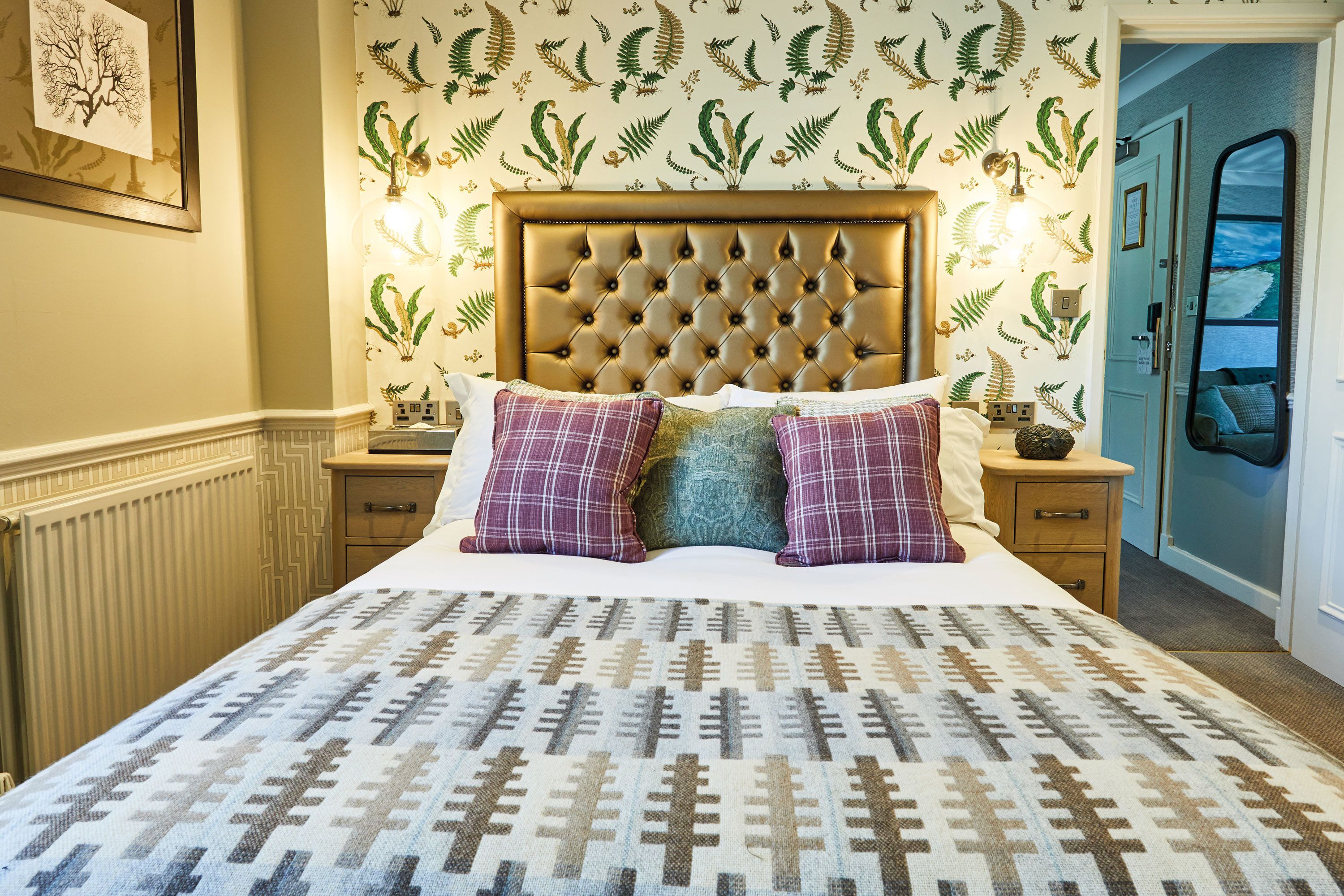 A bed with a tufted headboard, patterned bedding, and decorative pillows.