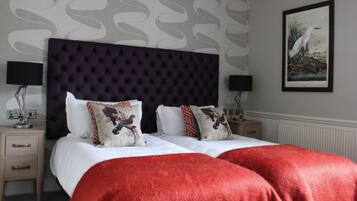 A neatly made double bed with a dark headboard, two bedside tables with lamps, and a framed painting on the wall.