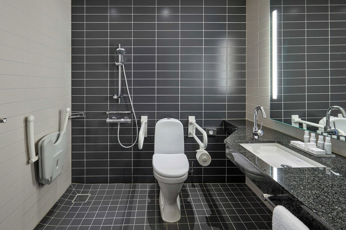 A modern bathroom with a white toilet, a shower, and a sink with a mirror.