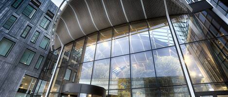 En moderne bygning med en buet glasfacade og en markant indgang med et metalbaldakin.