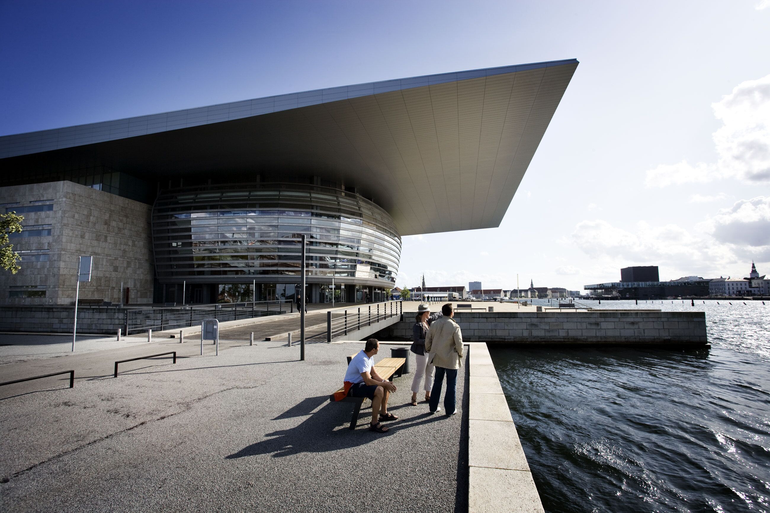 A waterfront building with a curved facade and a large overhanging roof.
