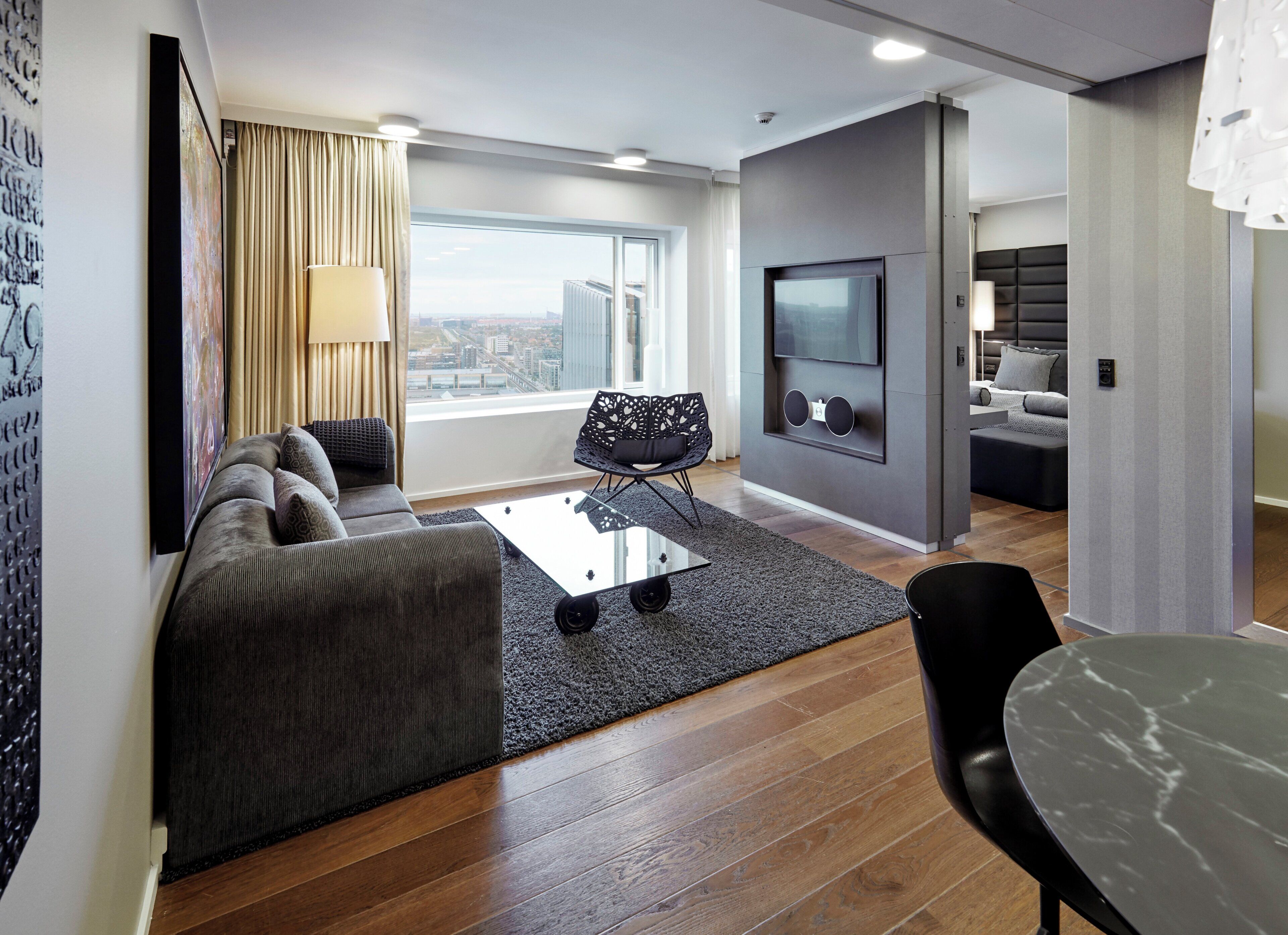 A modern living room with a sofa, a coffee table, and a TV mounted on the wall.