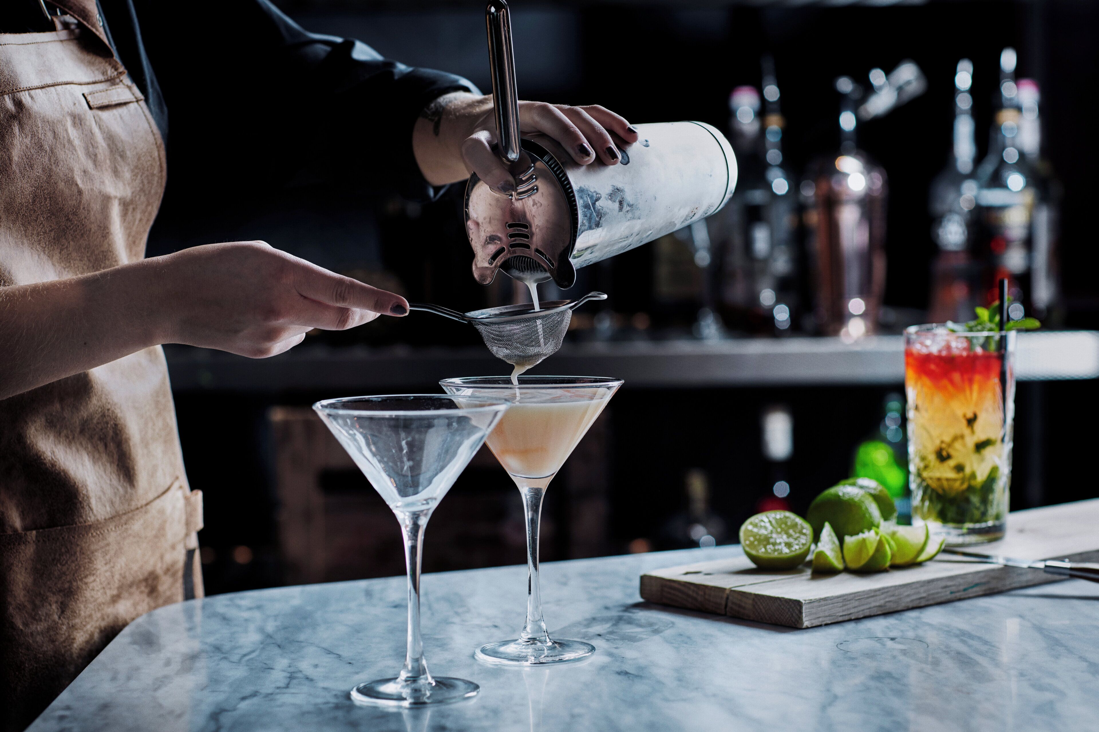 Un barman verse une boisson dans un verre à martini.