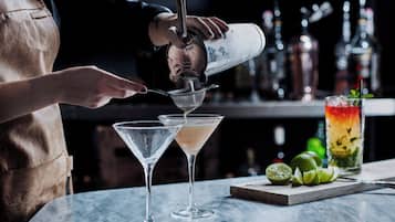 Un barman verse une boisson dans un verre à martini.
