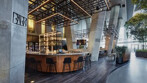 Un'area bar moderna con un bancone curvo, diversi sgabelli da bar e una vetrina piena di bottiglie.