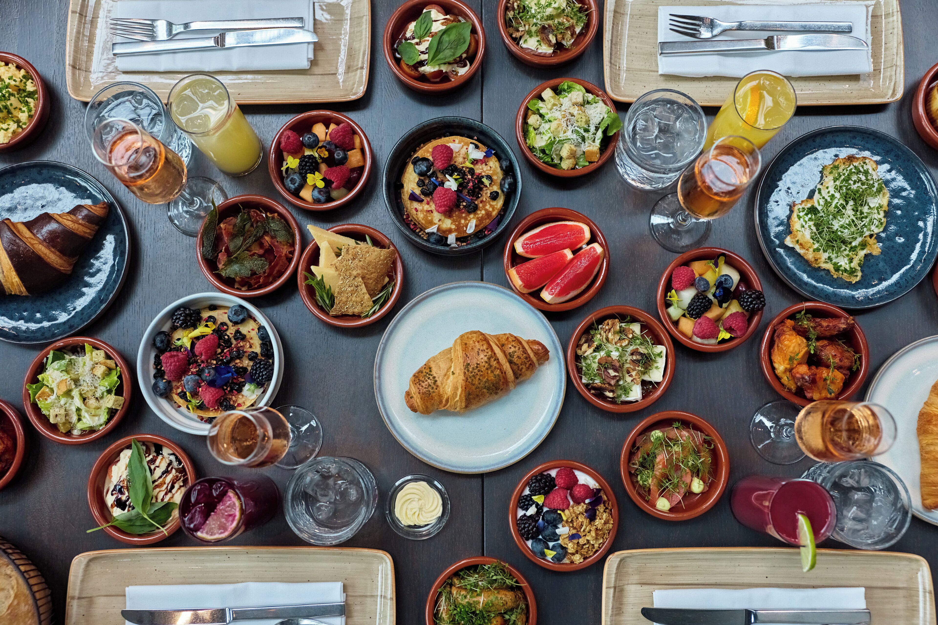 A variety of breakfast dishes, drinks, and utensils arranged on a table.
