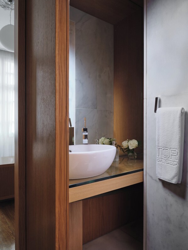 A bathroom with a wooden vanity, a white sink, a mirror, and a towel hanging on the wall.