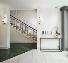 Un interior moderno con una escalera, una consola con velas y una columna.