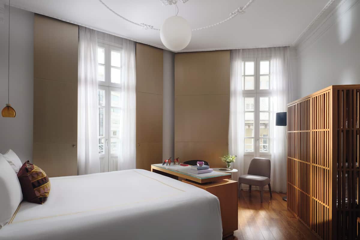 Una habitación de hotel con una cama grande, un escritorio, una silla y un armario.