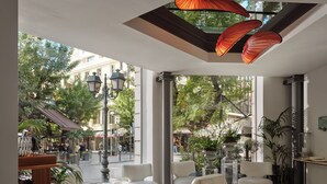 Un moderno vestíbulo de hotel con zona de estar, ventanas amplias y plantas de interior.