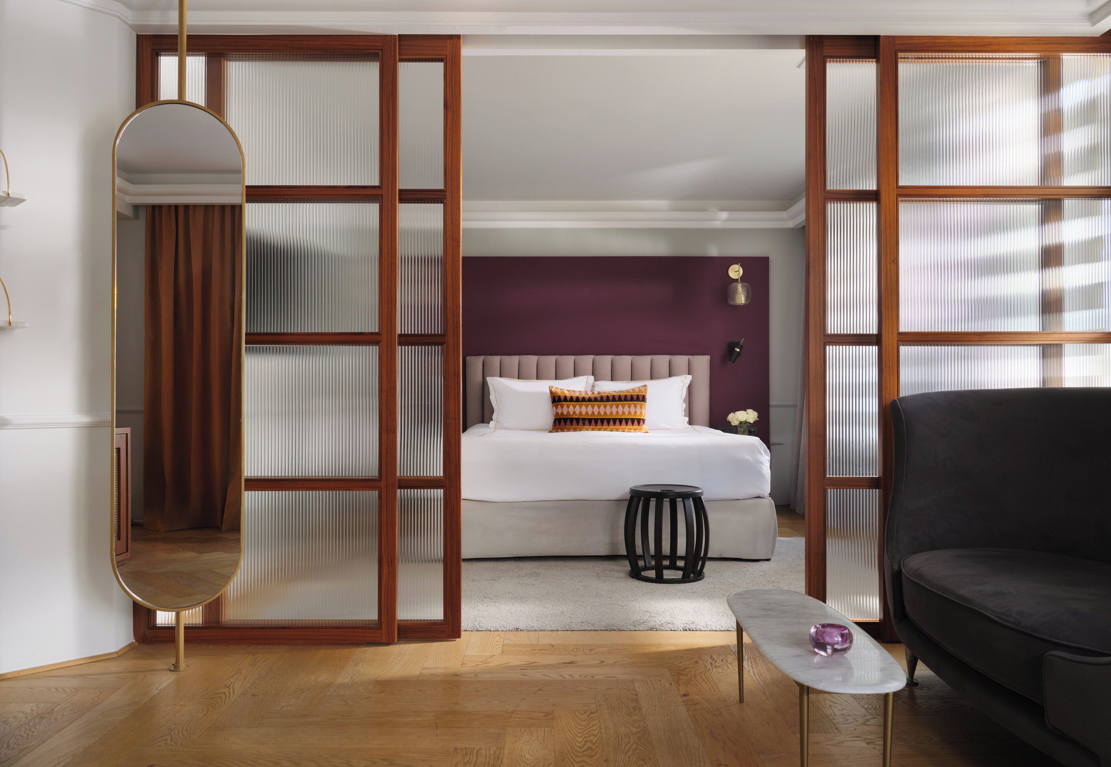 Un dormitorio con cama, mesita de noche, espejo y sofá.