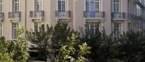 A multi-story building with balconies and large windows, surrounded by trees.