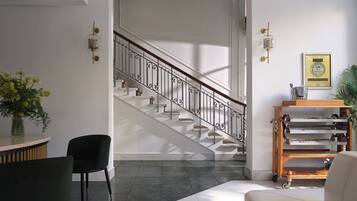 A spacious living area with a staircase, a dining table with chairs, and a sofa.