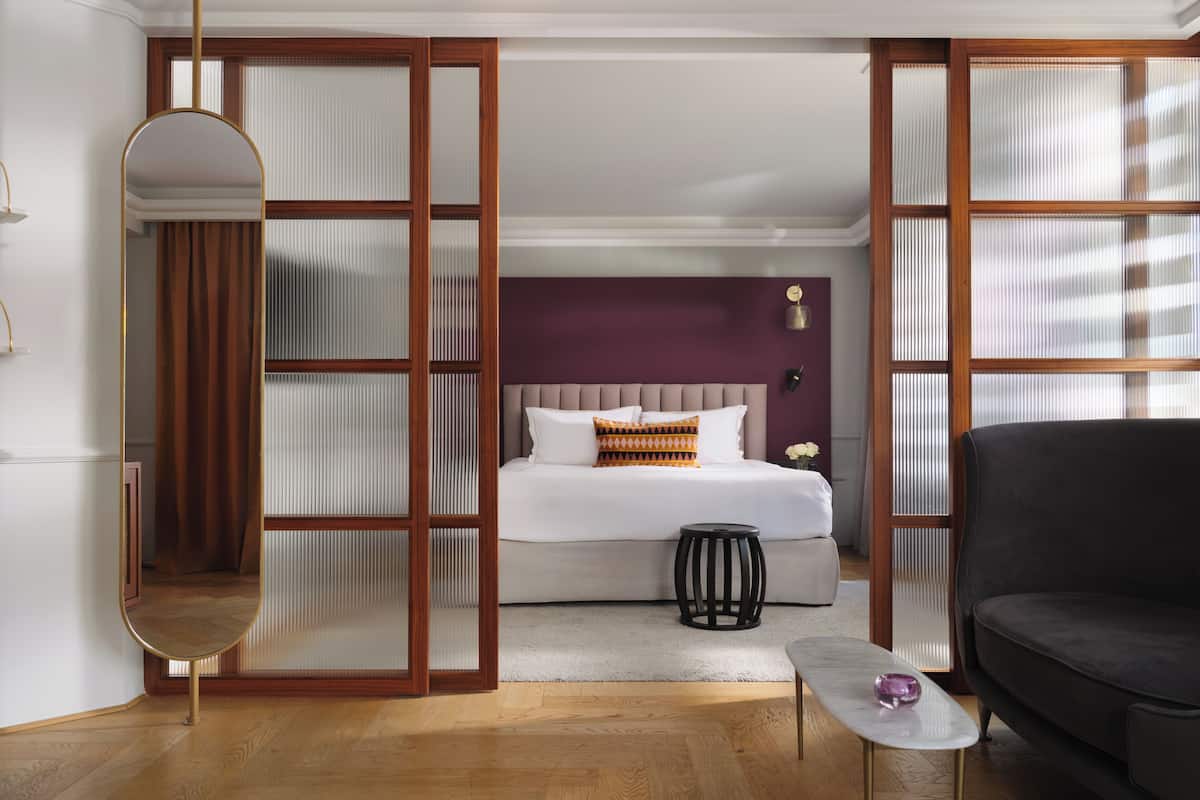Una habitación de hotel con cama, una mesita, un sofá y un espejo.