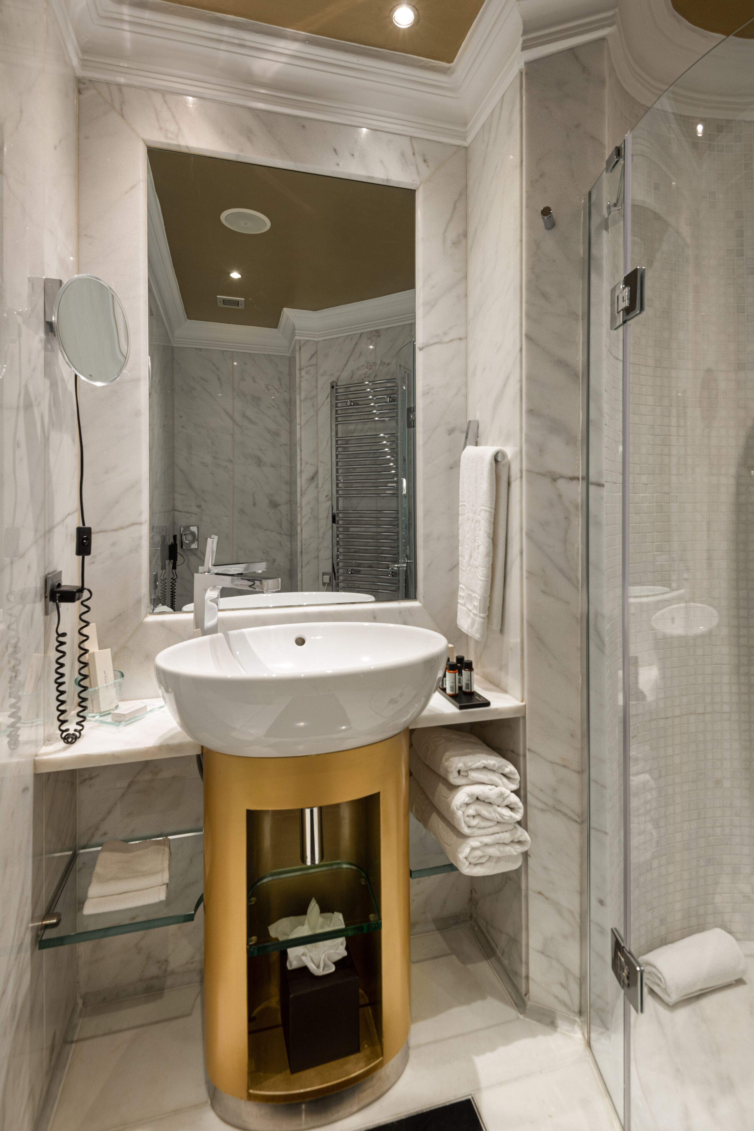Un baño moderno con un lavamanos grande, cabina de ducha con mampara de vidrio y un espejo.