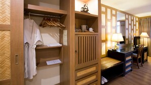 Een hotelkamer met een houten garderobe, een bureau met een lamp en een stoel.