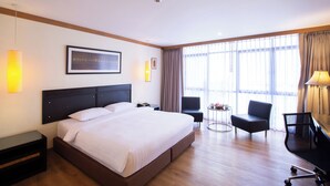 Een hotelkamer met een groot bed, een bureau, twee stoelen en een raam met gordijnen.