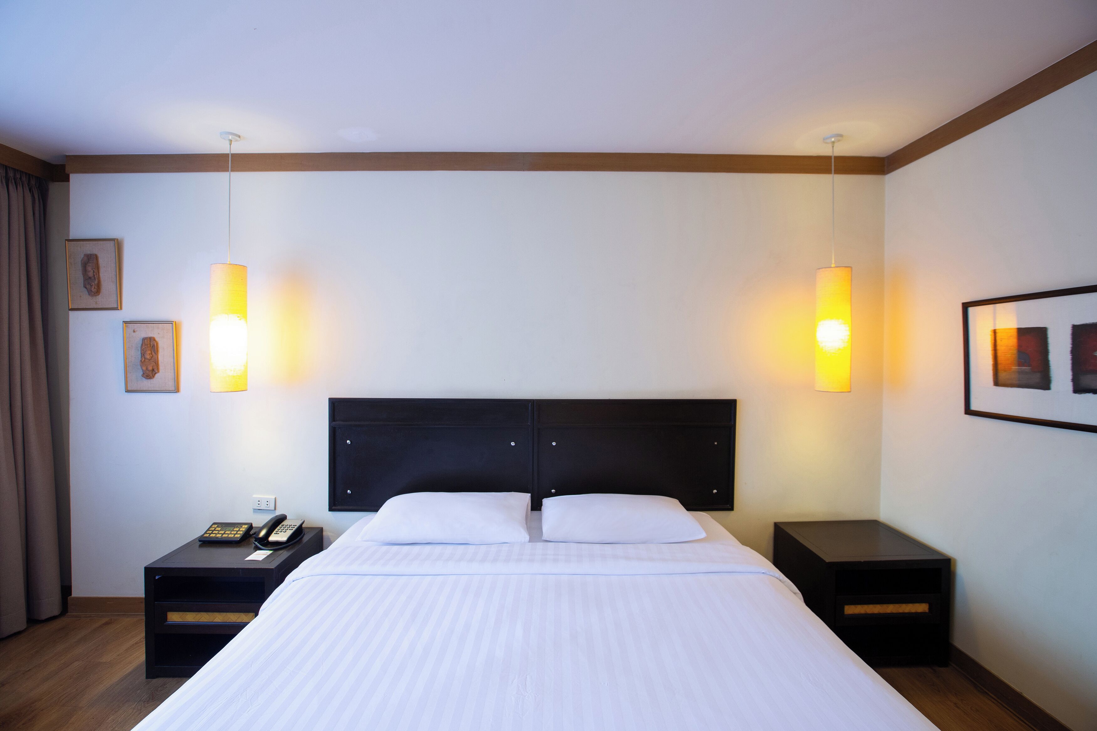 Una camera d'albergo con un letto grande, due comodini, un telefono e lampade a parete.