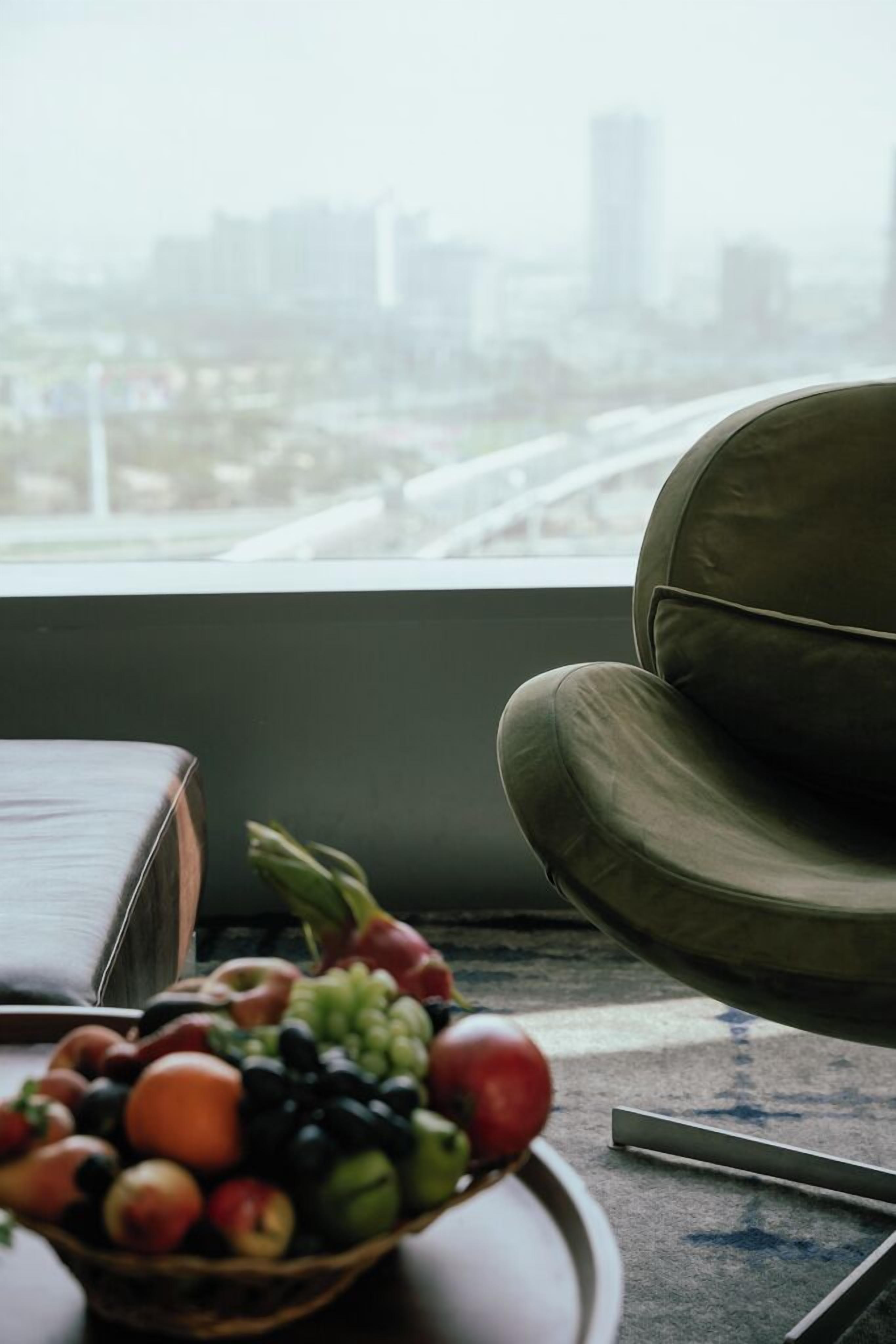 A bowl of fruit on a table near a window with a cityscape view.