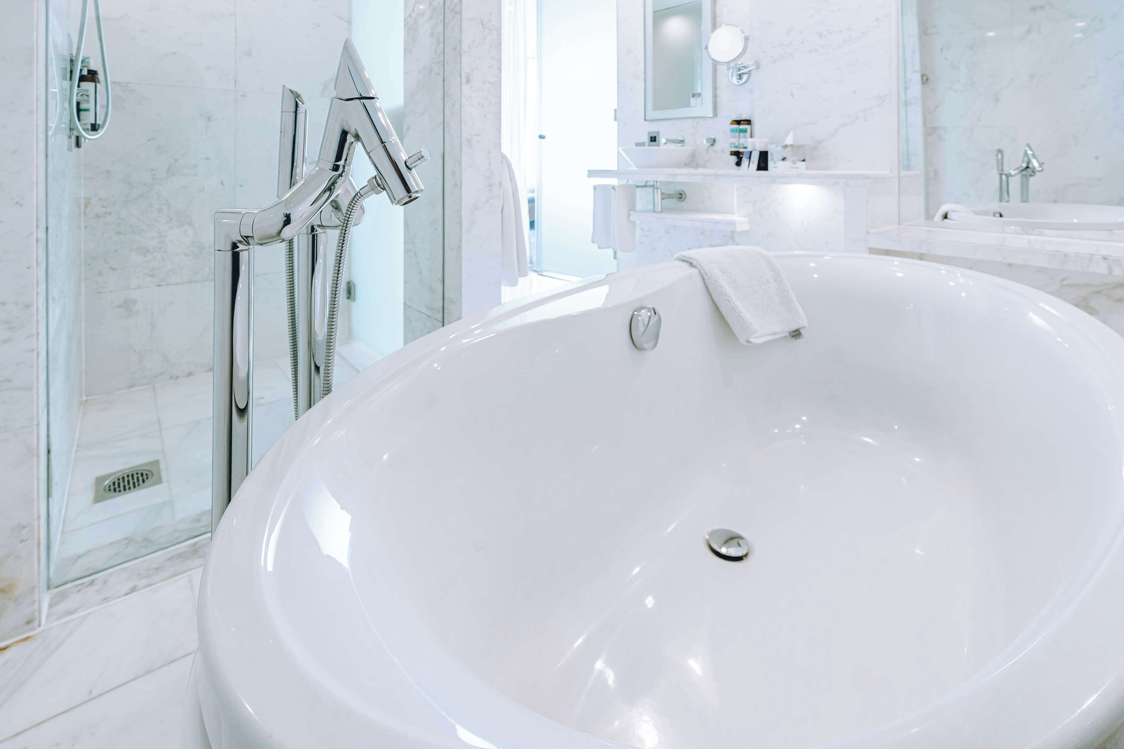 Un baño moderno con una bañera grande, ducha y tocador con espejo.
