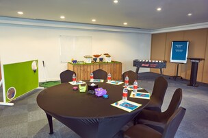 A conference room with a round table, chairs, a podium, and a whiteboard.