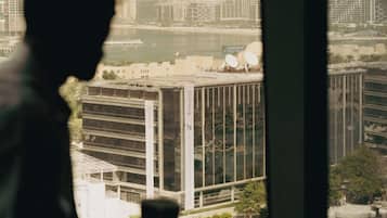 Silueta de una persona sosteniendo una taza, con vista a un paisaje urbano a través de una ventana.