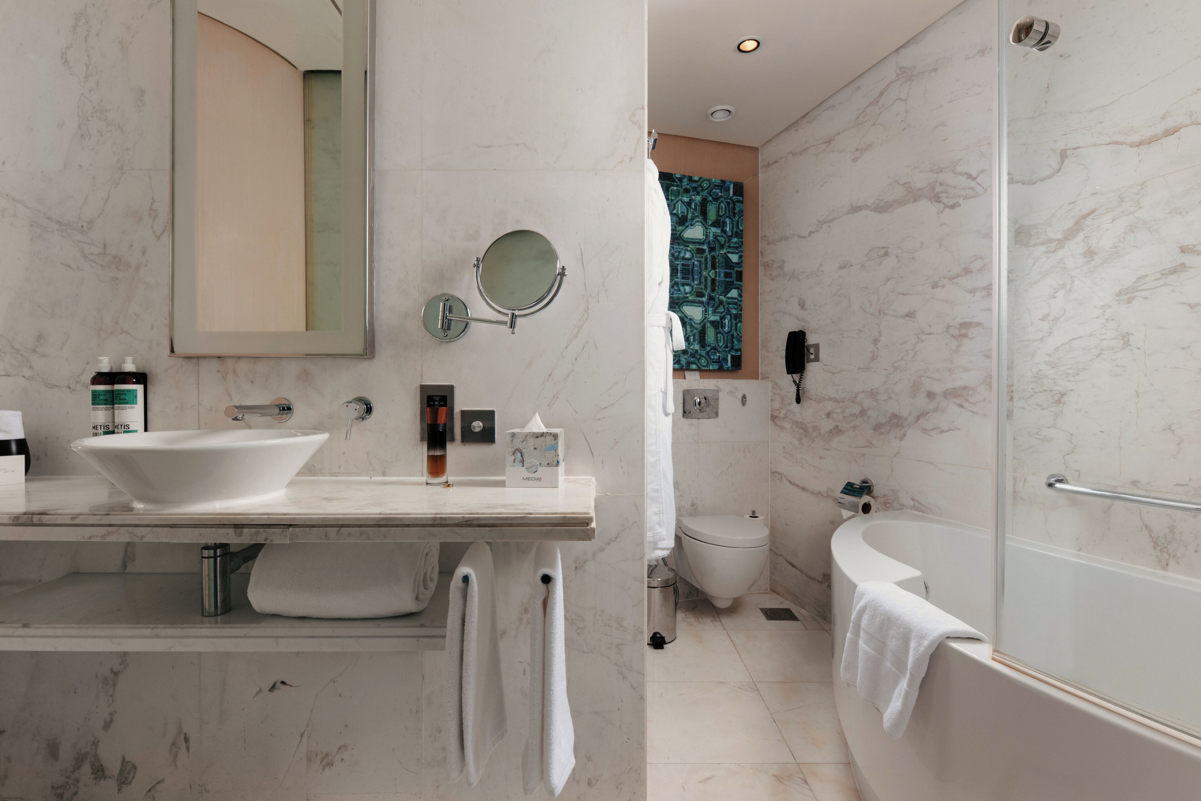 A modern bathroom with a double sink, a large mirror, a toilet, and a bathtub.
