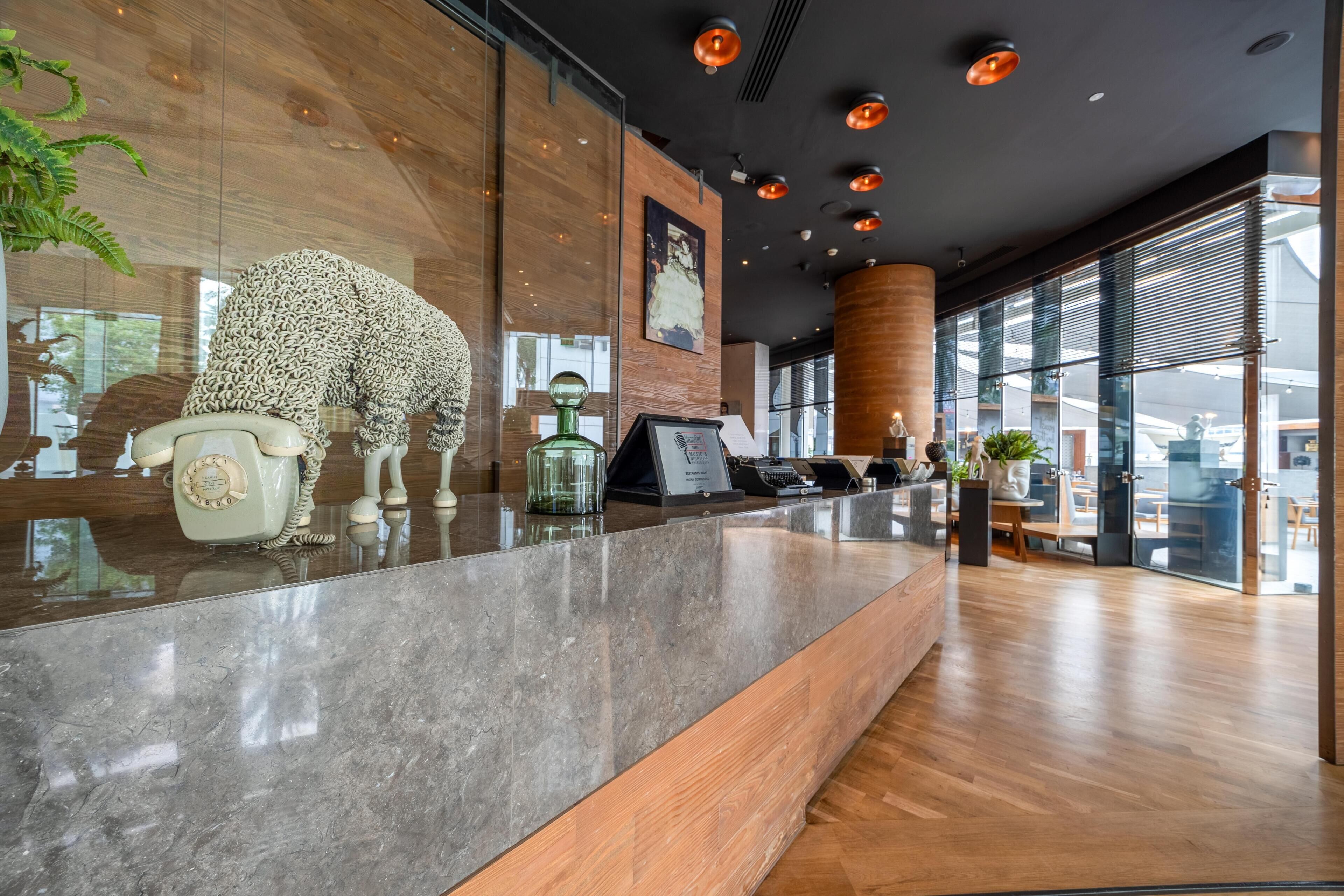 A reception desk with a telephone, a glass vase, and a decorative sculpture.