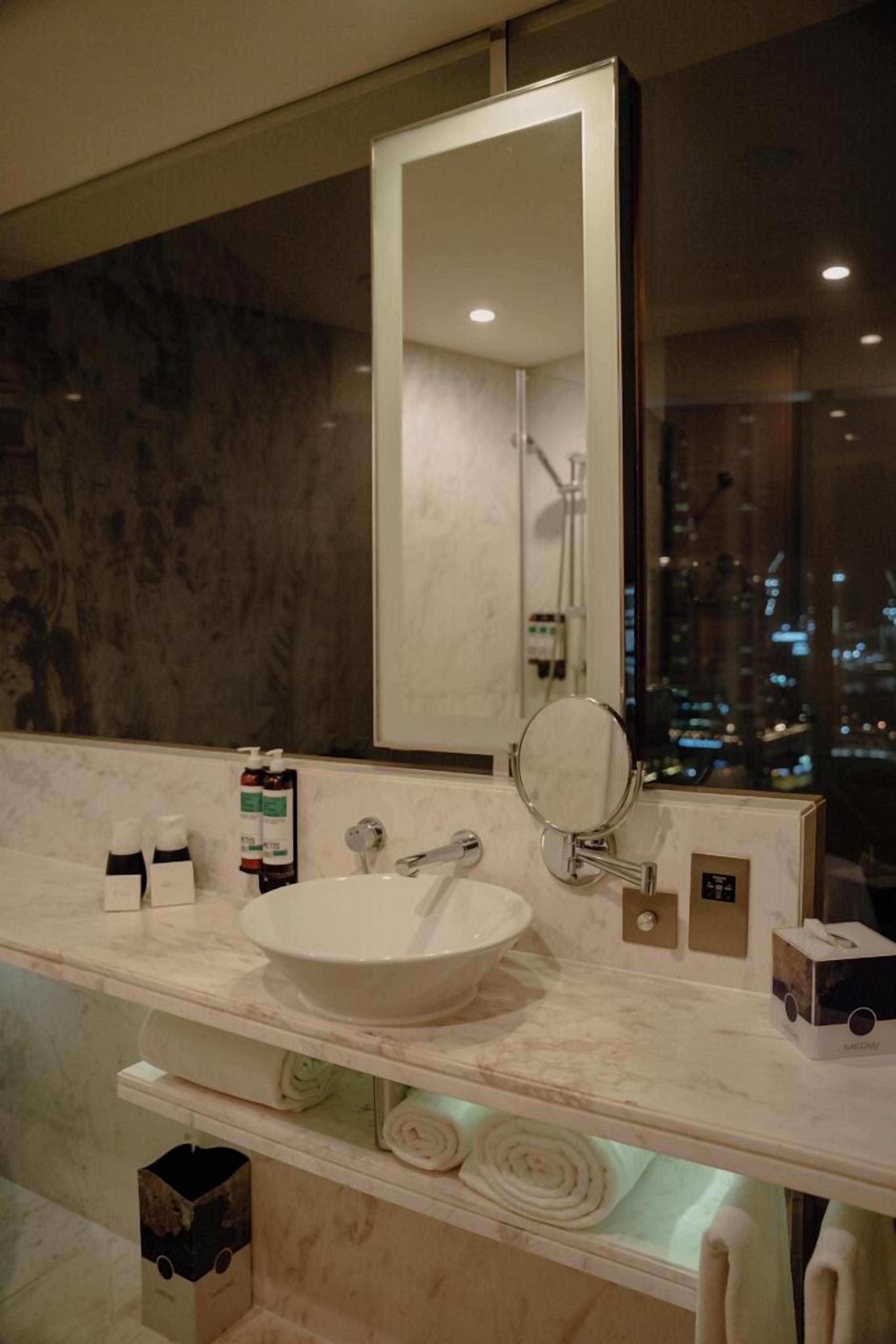 A bathroom with a large mirror, a white sink, and a towel rack.