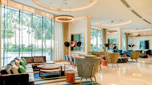A spacious lobby with a seating area, large windows, and a modern chandelier.