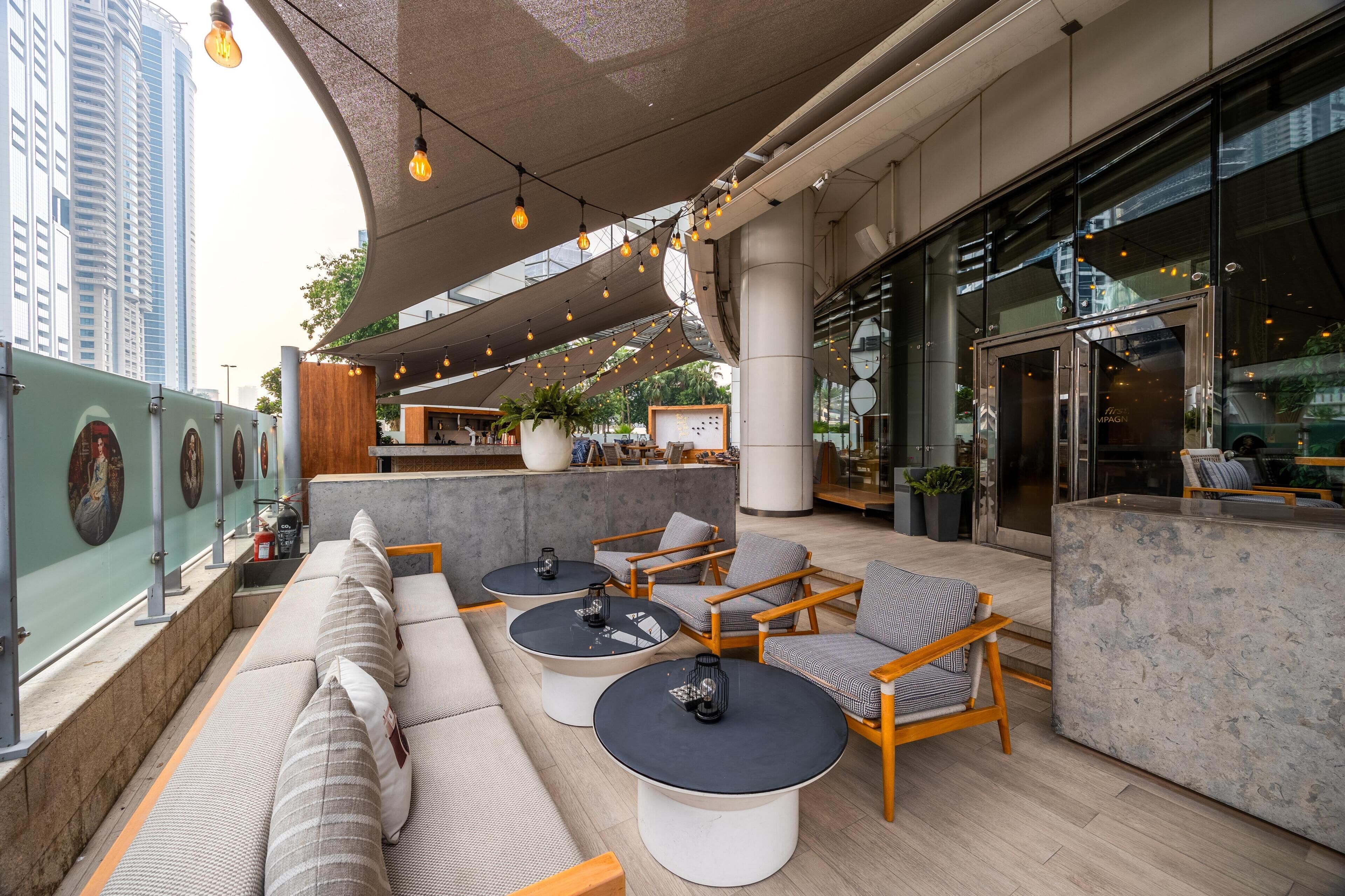 A rooftop terrace with outdoor seating, a bar area, and a view of the cityscape.