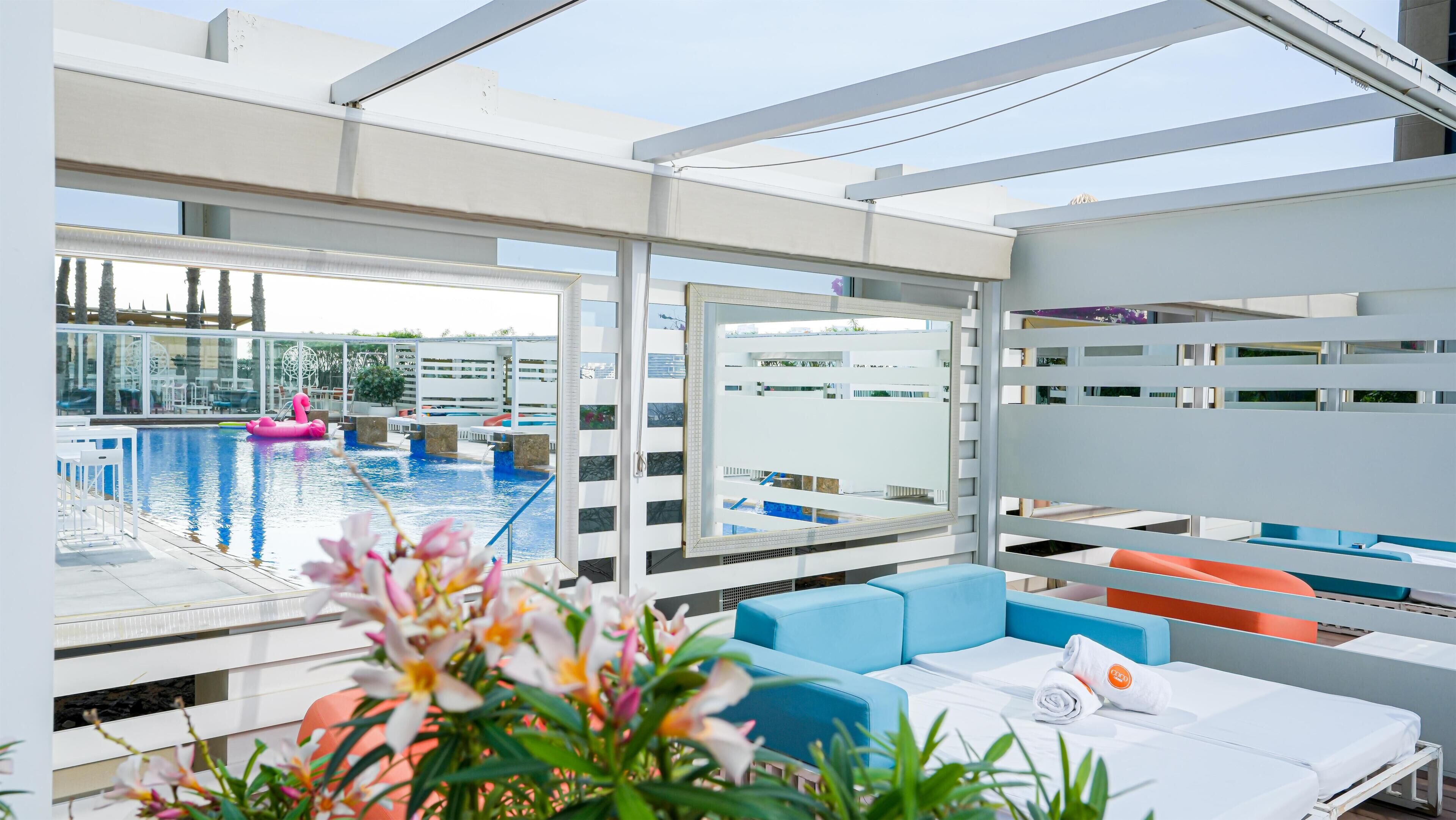 A modern hotel room with a pool view, a balcony, and a seating area with a view.