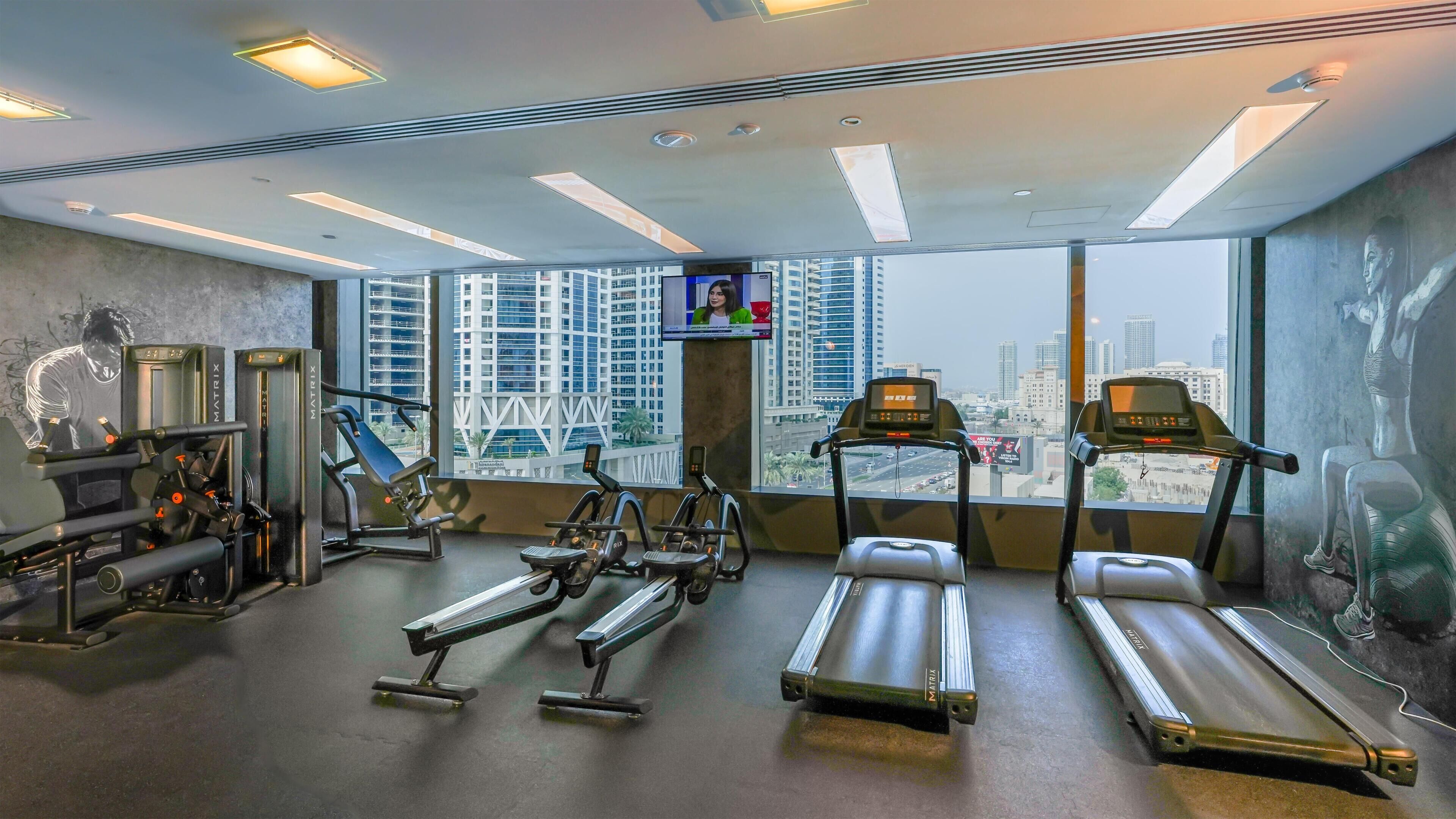 Un gimnasio con cintas de correr, elípticas y equipo de pesas.