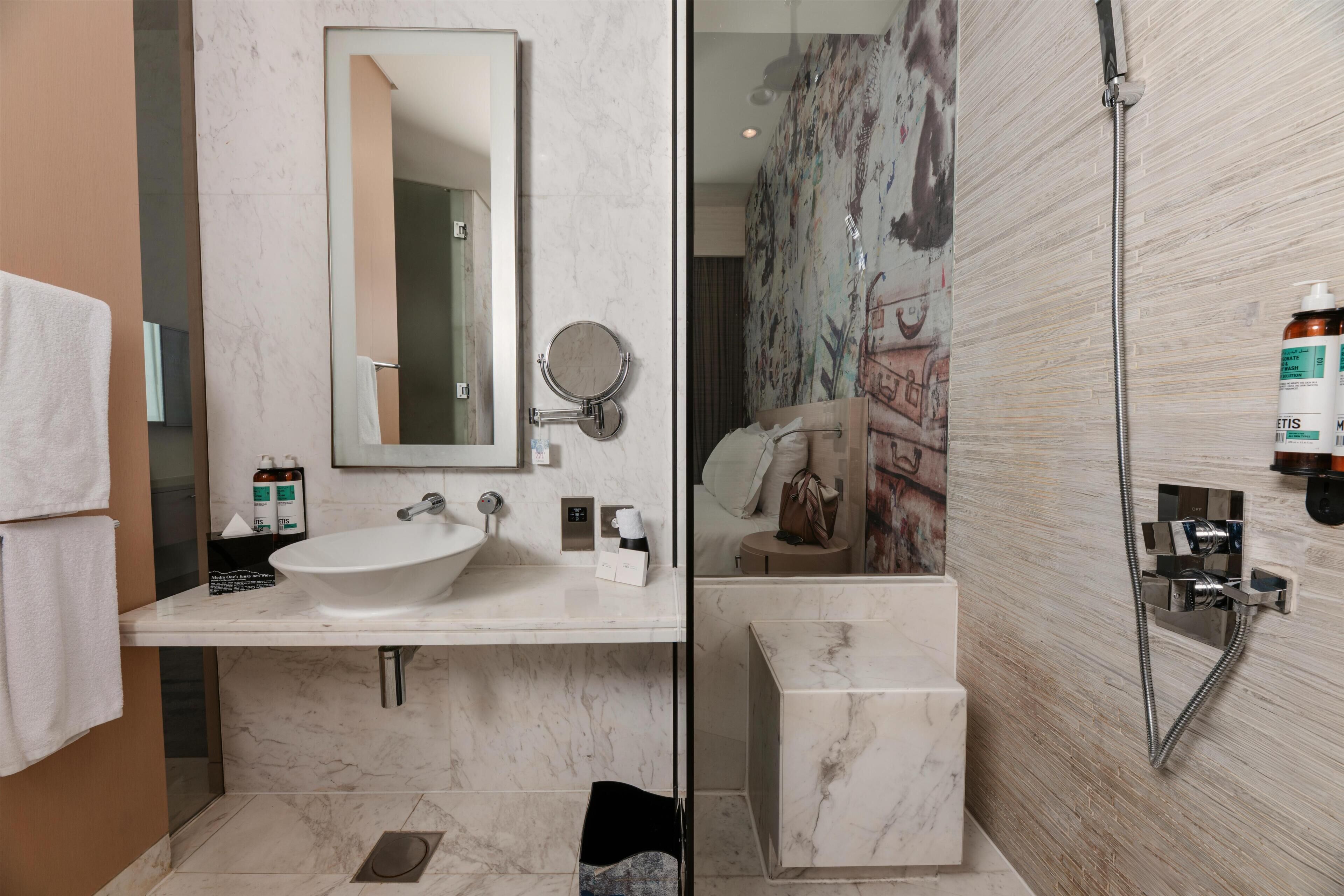 A bathroom with a sink, mirror, and shower.