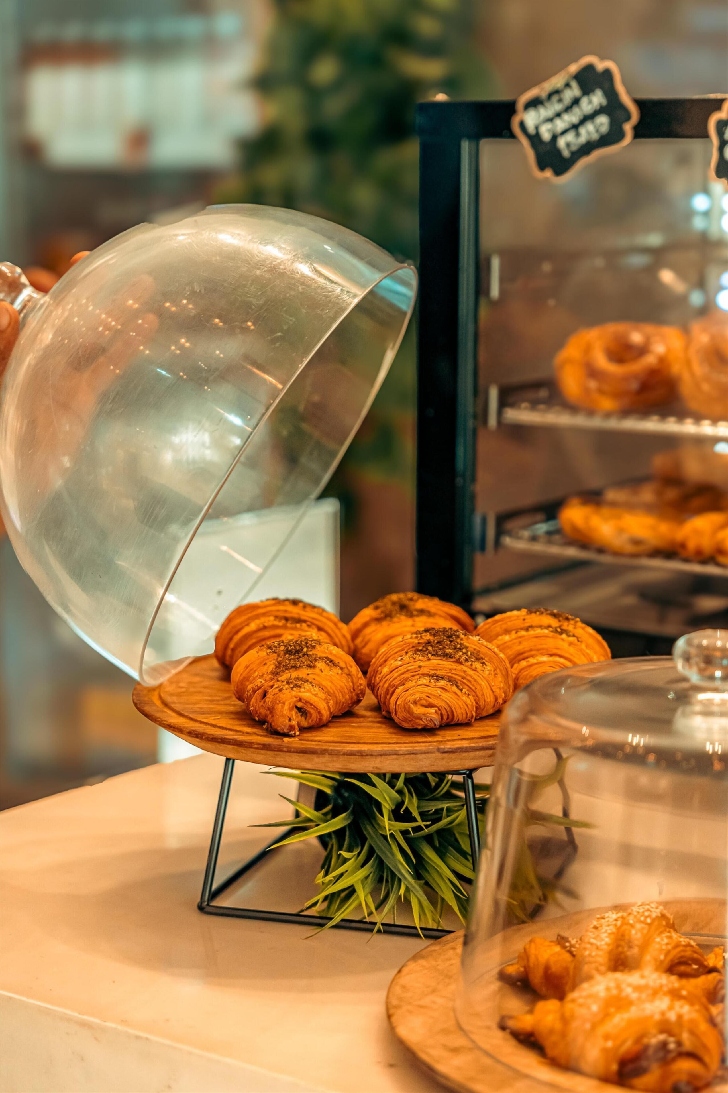 A bakery display with pastries, a glass dome, and a sign indicating 'Pancake French Toast'.