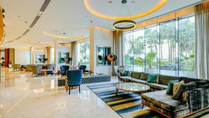 A spacious lobby with a modern design, featuring a seating area with sofas and chairs, a coffee table, and large windows offering a view of the outdoors. - Media One Hotel Dubai, WorldHotels Crafted (Dubai)