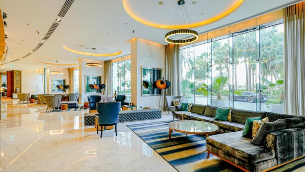 A spacious lobby with a modern design, featuring a seating area with sofas and chairs, a coffee table, and large windows offering a view of the outdoors. - Media One Hotel Dubai, WorldHotels Crafted (Dubai)
